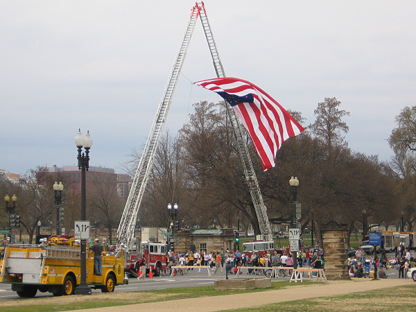 Fire trucks creating an arch with the American flag.